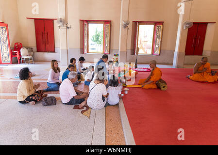 Phuket, Thailand, 04/19/2019 - Ein buddhistischer Mönch betet mit einer Familie an der Wat Chalong. Stockfoto