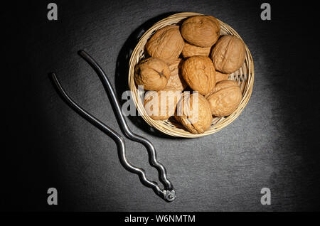 Walnüsse mit Nussknacker auf schwarzem Hintergrund, Ansicht von oben. Stockfoto