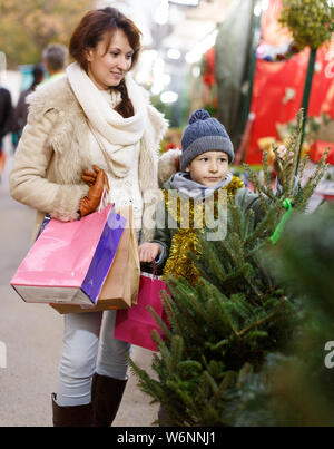 Happy school alter Junge mit seiner Mutter Auswahl frisch geschnittenen Xmas Tree am Markt im Freien Stockfoto