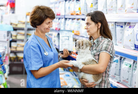 Ältere Menschen froh, heiter angenehme weibliche Tierarzt empfehlen Heimtierfutter junge Frau besucht Pet Store mit Ihrem Welpen Stockfoto