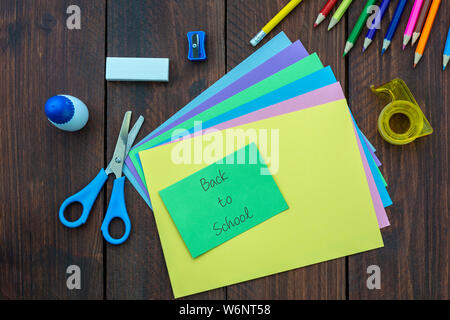 Farbiges Papier, Schere, Klebestift auf einer hölzernen Hintergrund. Zurück zu Schule Konzept Stockfoto