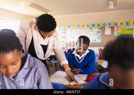 Lehrer Schüler helfen in eine Lektion an einem Township School Stockfoto