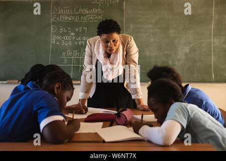 Lehrerin und junge Schülerinnen und Schüler arbeiten in der Klasse Stockfoto