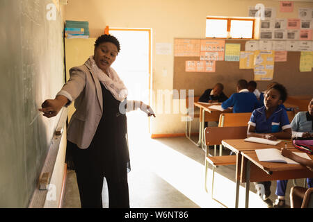 Lehrerin an der Tafel vor der Klasse Stockfoto