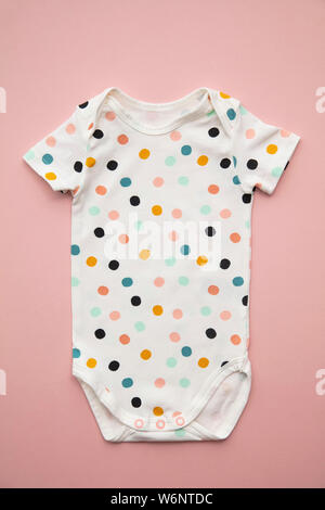 Cute Polka Dot Baby Body Suit Layout auf ein Pastell rosa Hintergrund Stockfoto