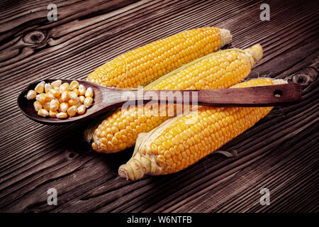 Maiskörner in hölzernen Löffel über frischen süßen Bio Hühneraugen auf Holz rustikal Tisch gelegt. Gesunde Ernährung Konzept. Stockfoto