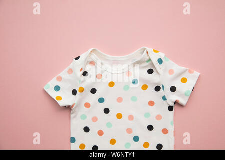 Cute Polka Dot Baby Body Suit Layout auf ein Pastell rosa Hintergrund Stockfoto