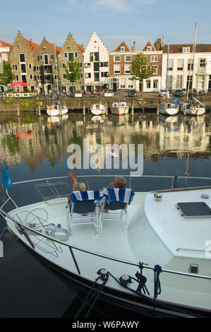 Ein paar sitzen auf Ihrem Boot und schauen sich die Kinderdijk mit historischen Gebäuden in der Stadt Middelburg, Niederlande Stockfoto