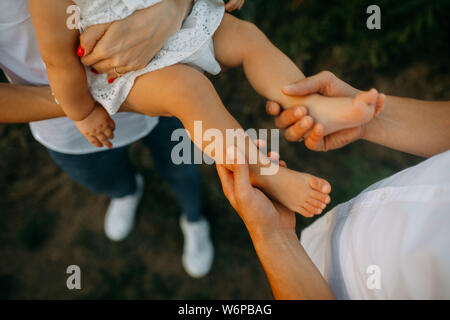 Hände von Vater halten Beine seine kleine Tochter. Nahaufnahme. Stockfoto