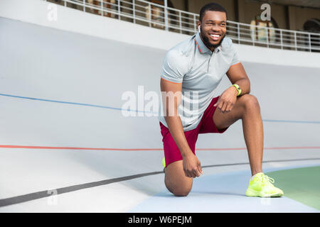 Hübscher junger männlicher Läufer stehen auf einem Knie Stockfoto