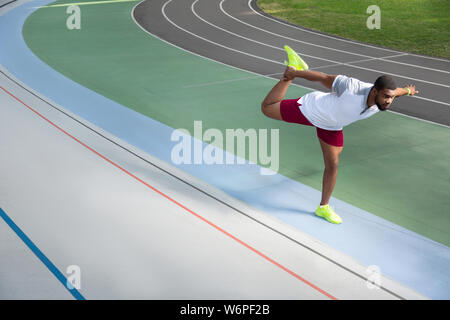 Hübscher junger Athlet seine Beine strecken konzentriert Stockfoto