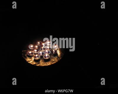 Gruppe von kleinen Kerzen leuchten in einer dunklen Nacht sitzen auf einer Amtsleitung, ihre Schönheit zeigt. Auf dem braunen Stuhl Sie die Beleuchtung der Zimmer Stockfoto