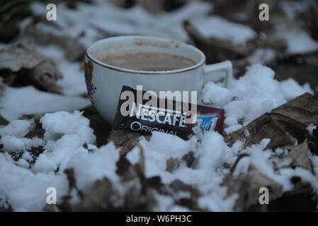 Tasse Nescafe im Winter kühlen mit Schnee Tasse Kaffee und Kuchen Pause Zeit in kaltem Wetter Kaffee trinken Blätter um Snowy White Snow Nescafe Stockfoto