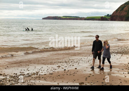 Paar, Mann und Frau zu Fuß/entlang Sidmouth Strand - welche Bereiche von Sand und Kies - unten sandige Steilküste im Westen von Jacobs Leiter hat bummeln. (110) Stockfoto