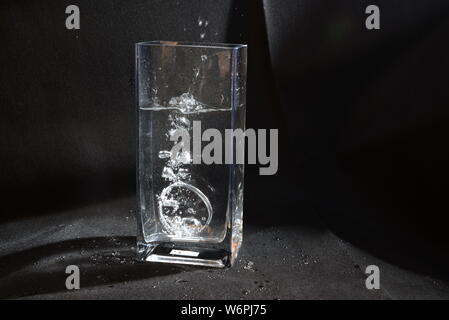 Professionelle foto Zubehör drop im Moment der herabhängend und Blasen im Wasser zu Wasser Stockfoto