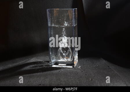 Professionelle foto Zubehör drop im Moment der herabhängend und Blasen im Wasser zu Wasser Stockfoto