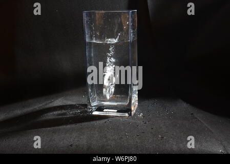 Professionelle foto Zubehör drop im Moment der herabhängend und Blasen im Wasser zu Wasser Stockfoto