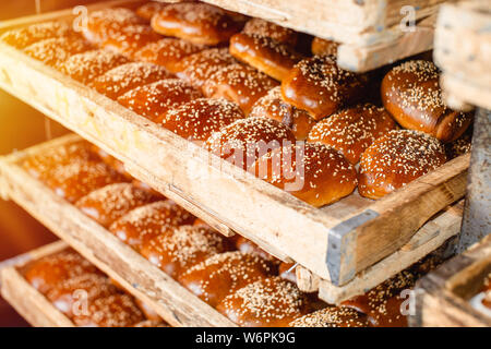 Holzregale mit frischem Gebäck in einer Bäckerei. Sesam Brötchen. Stockfoto