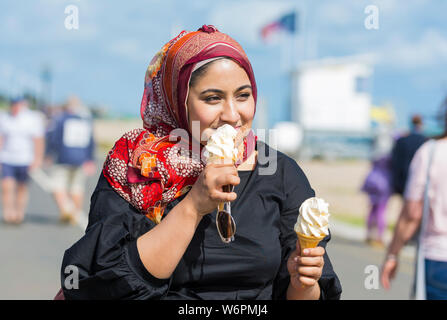 Junge asiatische Frau Essen a 99 Eis am Meer im Sommer in Großbritannien. Stockfoto