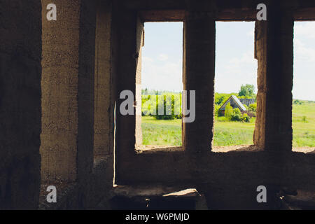 Die zerstörte große Gebäude aus Beton in einer nebligen Dunst. Die Überreste der Rahmen des grauen Betonpfeilern und Ablagerungen von der Gebäudestruktur. Hintergrund. Stockfoto