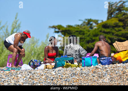 Eine schwarze Familie zusammen an einem Strand an einem warmen Frühlingstag in West Sussex, England, UK.