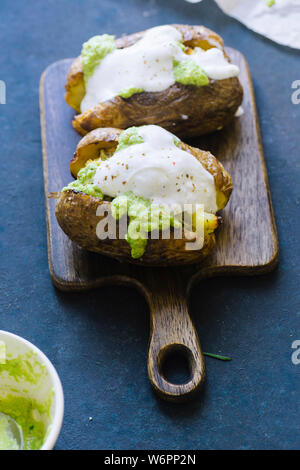 Doppelt gebackene Kartoffeln mit Frühlingszwiebeln, Knoblauch und Olivenöl mit grünem Pesto serviert. Stockfoto