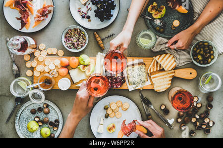 Saisonale Mitte Sommer Picknick oder Party mit Wein und Snacks. Flachbild-lay von Wurst- und Käseplatte mit verschiedenen Vorspeisen, Rose Wein, Nüsse, Oliven ein Stockfoto