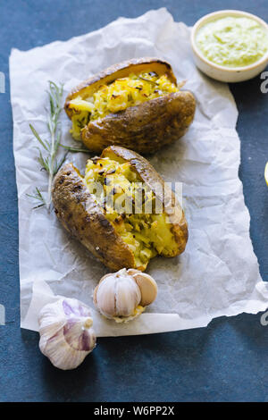 Doppelt gebackene Kartoffeln mit Frühlingszwiebeln, Knoblauch und Olivenöl mit grünem Pesto serviert. Stockfoto