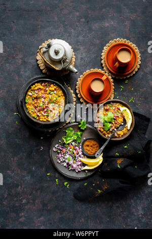 Indische Linsensuppe vegan Curry mit gehackten Zwiebeln, grüner Chili, Koriander, frisch gemahlene Gewürze serviert und frisch Chai. Stockfoto