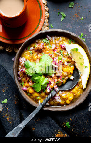 Indische Linsensuppe vegan Curry mit gehackten Zwiebeln, grüner Chili, Koriander, frisch gemahlene Gewürze serviert und frisch Chai. Stockfoto