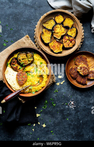 Bengali Khichdi - Linsen, Hirse Suppe - eine Glutenfreie vegane Mahlzeit serviert mit sautierten Aubergine, Mohn Krapfen, und papadum. Stockfoto