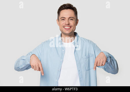 Glückliche Menschen auf grauem Hintergrund isoliert Pointing Finger nach unten Stockfoto