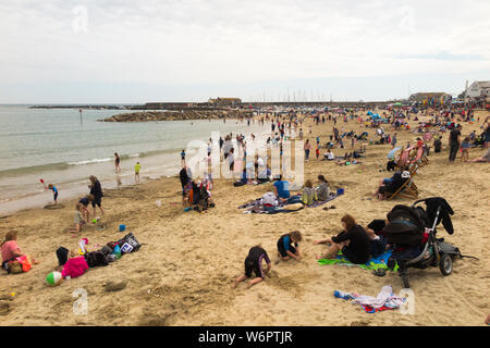 Lyme Regis Sandstrand im Frühjahr/Frühsommer an einem warmen Tag grau mit vielen Urlauber genießen das Meer und den Sand. Lyme Regis, England UK. (110) Stockfoto