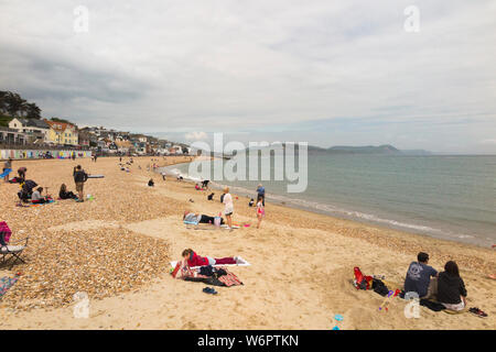 Lyme Regis Sandstrand im Frühjahr/Frühsommer an einem warmen Tag grau mit vielen Urlauber genießen das Meer und den Sand. Lyme Regis, England UK. (110) Stockfoto