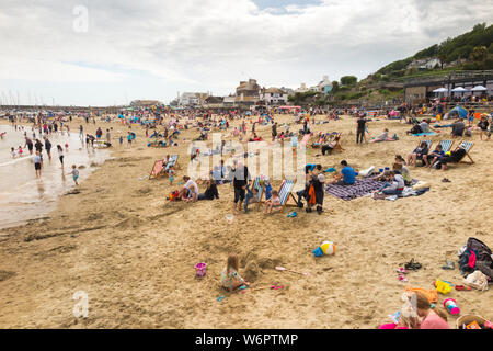 Lyme Regis Sandstrand im Frühjahr/Frühsommer an einem warmen Tag grau mit vielen Urlauber genießen das Meer und den Sand. Lyme Regis, England UK. (110) Stockfoto