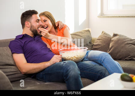 Verliebtes paar Popcorn zu essen und Spaß zu haben, während Sie Zeit miteinander zu verbringen bei sich zu Hause genießen. Stockfoto