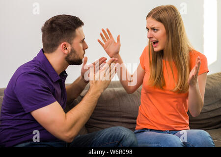 Böse Frau und Mann sind in Konflikt, während Sie auf dem Sofa zu Hause sitzen. Stockfoto