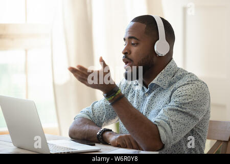 Afrikanische Mann skype Lehrerin das Tragen von Kopfhörern sprechen am Laptop suchen Stockfoto