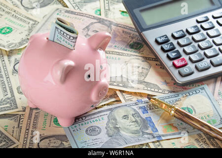 United States Banknoten und Münzen mit einem Taschenrechner, Stift, und piggy Bank Stockfoto