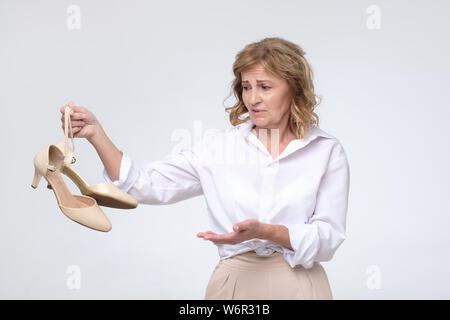 Müde business Frau in weißem Hemd mit unbequemen High Heels. Stockfoto