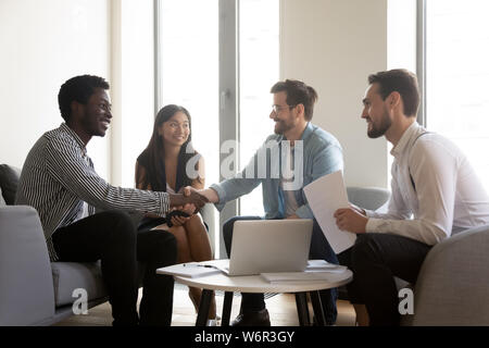 Lächelnd diverse männliche Vertreter des Unternehmens handshaking auf multiethnische Gruppe Sitzung Stockfoto