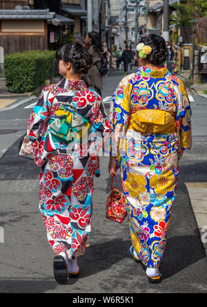 Zwei junge japanische Frauen, die traditionelle Kimonos, hinunter eine Straße im Stadtteil Gion, Kyoto, Japan Stockfoto