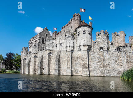 Gent, Flandern, Belgien - 21. Juni 2019: grauen Stein Burg und Stadtmauer von Gravensteen, historischen mittelalterlichen Burg der Stadt, hinter seiner Moad gegen Blu Stockfoto