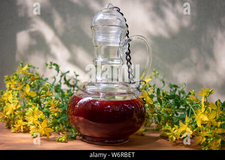 Eine Flasche roten Öl aus Johanniskraut Blüten erfolgen, im Freien Stockfoto