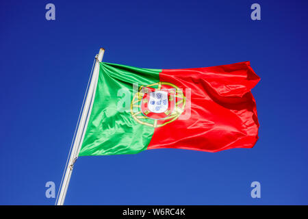 Flagge Portugals flattern im Wind gegen leeren blauen Himmel. Stockfoto