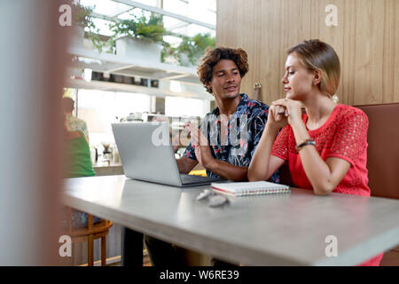 Candid lifestyle Schuß von attraktiven multi-ethnischen tausendjährigen Freunde in 20 s am Stand der modernen hellen tropischen Hipster cafe Brainstorming Stockfoto