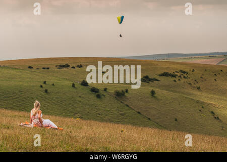 Devils Dyke, Brighton, East Sussex, Großbritannien. Aug. 2019. Ein glorreicher Nachmittag mit einer nördlichen Brise sieht Gleitschirmflieger und Zuschauer am beliebten Veranstaltungsort in den South Downs nördlich von Brighton. Stockfoto