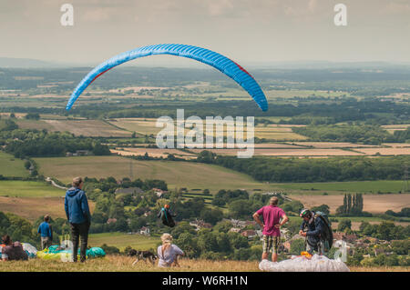 Devils Dyke, Brighton, East Sussex, Großbritannien. Aug. 2019. Ein glorreicher Nachmittag mit einer nördlichen Brise sieht Gleitschirmflieger und Zuschauer am beliebten Veranstaltungsort in den South Downs nördlich von Brighton. Stockfoto