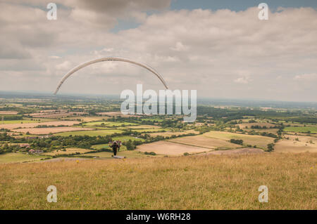 Devils Dyke, Brighton, East Sussex, Großbritannien. Aug. 2019. Ein glorreicher Nachmittag mit einer nördlichen Brise sieht Gleitschirmflieger und Zuschauer am beliebten Veranstaltungsort in den South Downs nördlich von Brighton. Stockfoto