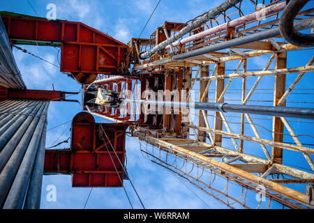 Bohrinsel Derrick im Ölfeld gegen den strahlend blauen Himmel. Bohranlage in Öl Feld für Bohrungen in den Untergrund, um Erdöl produziert. Petroleum I Stockfoto